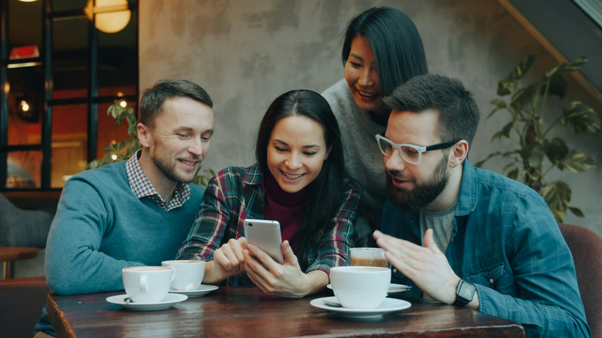 A group of friends sitting together, laughing and looking at a phone